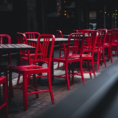 Tavolini con sedie rosse su un marciapiede